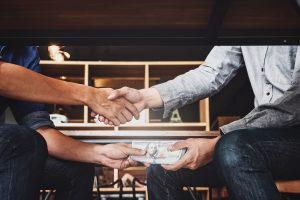 Shaking hands exchanging money, hire ethical financial advisors in the dc area